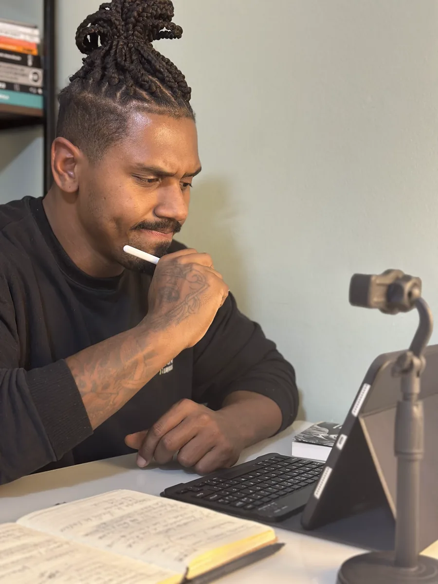 Christian Soares montando um treino no tablet, com o caderno de anotações aberto na mesa
